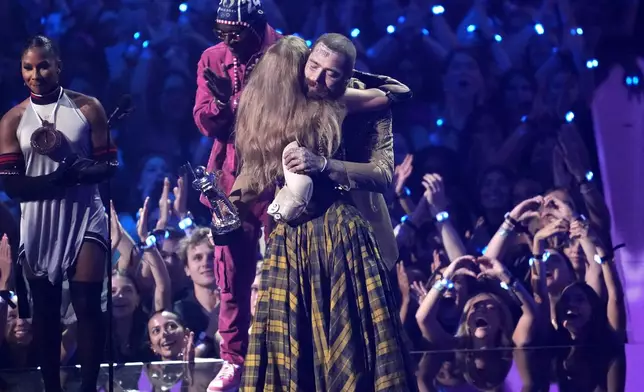 Taylor Swift, center, and Post Malone embrace as they accept the award for best collaboration for "Fortnight" during the MTV Video Music Awards on Wednesday, Sept. 11, 2024, at UBS Arena in Elmont, N.Y. Jordan Chiles, far left, and Flava Flav look on.(Photo by Charles Sykes/Invision/AP)