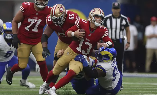 San Francisco 49ers quarterback Brock Purdy (13) is tackled by Los Angeles Rams defensive tackle Braden Fiske, bottom middle, and defensive tackle Kobie Turner, bottom right, during the second half of an NFL football game, Sunday, Sept. 22, 2024, in Inglewood, Calif. (AP Photo/Ryan Sun)