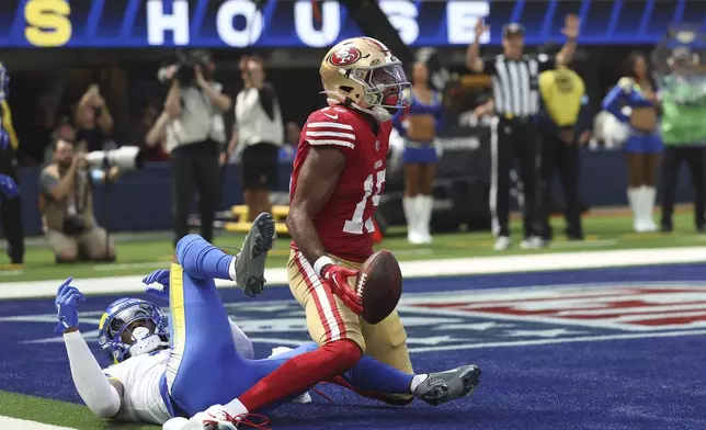 San Francisco 49ers wide receiver Jauan Jennings, middle, reacts after catching a touchdown pass in front of Los Angeles Rams safety Kamren Curl during the first half of an NFL football game, Sunday, Sept. 22, 2024, in Inglewood, Calif. (AP Photo/Ryan Sun)