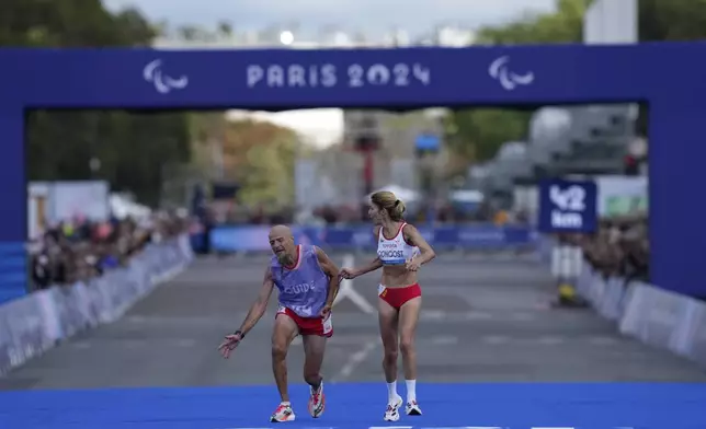 ADDITION ELENA CONGOST WAS DISQUALIFIED FOR LETTING GO OF THE ROPE TO HELP HER GUIDE - Spain's Elena Congost, right, arrives in third position in the women's marathon T12 at the 2024 Paralympics, Sunday, Sept. 8, 2024, in Paris, France. (AP Photo/Thibault Camus)