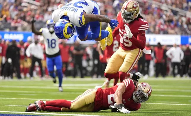 Los Angeles Rams running back Kyren Williams, top, flips into the end zone to score against San Francisco 49ers safety Talanoa Hufanga, bottom, and linebacker De'Vondre Campbell during the first half of an NFL football game, Sunday, Sept. 22, 2024, in Inglewood, Calif. (AP Photo/Ashley Landis)