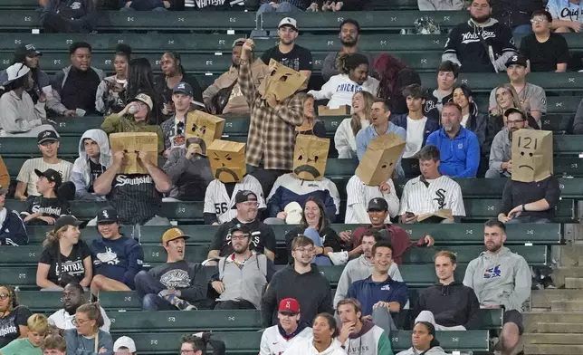 Chicago White Sox fans sit in the stands with bags on their head during the 10th inning of a baseball game between the White Sox and the Los Angeles Angels, Wednesday, Sept. 25, 2024, in Chicago. (AP Photo/David Banks)