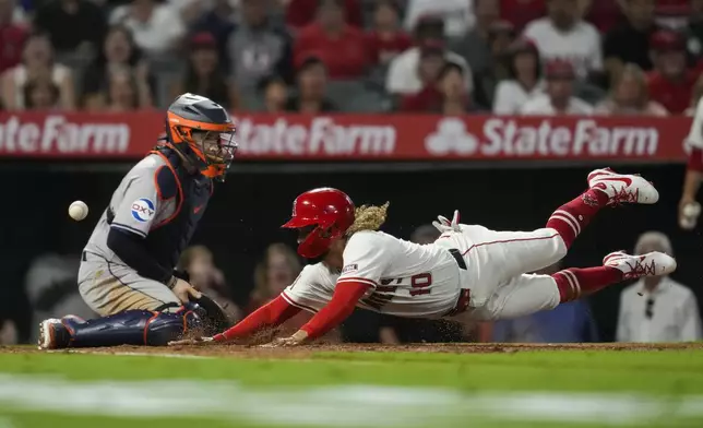 Los Angeles Angels' Jack López (10) scores as a throw gets past Houston Astros catcher Victor Caratini, left, during the third inning of a baseball game in Anaheim, Calif., Friday, Sept. 13, 2024. (AP Photo/Ashley Landis)