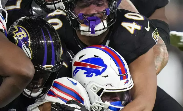 Baltimore Ravens linebacker Malik Harrison (40) and teammates help bring down Buffalo Bills running back Ray Davis, bottom, during the second half of an NFL football game, Sunday, Sept. 29, 2024, in Baltimore. (AP Photo/Stephanie Scarbrough)