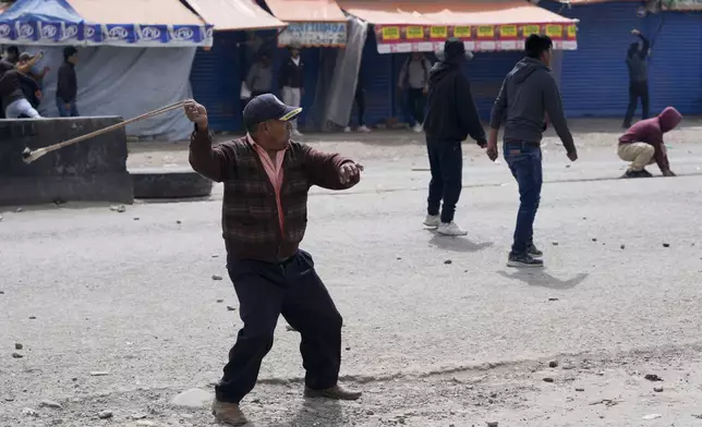 A supporter of former President Evo Morales slings a rock at supporters of current President Luis Arce in El Alto, Bolivia, Sunday, Sept. 22, 2024. (AP Photo/Juan Karita)