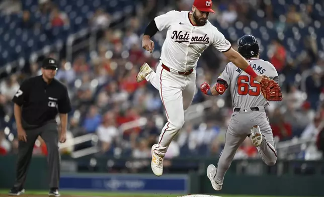 Washington Nationals first baseman Joey Gallo, center, cannot tag Atlanta Braves' Luke Williams on a throwing error during the third inning of a baseball game, Tuesday, Sept. 10, 2024, in Washington. (AP Photo/John McDonnell)