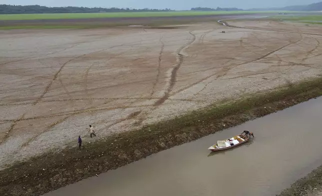 Fishermen push a boat in the Aleixo Lake during dry season in Manaus, Amazonas state, Brazil, Tuesday, Sept. 24, 2024. (AP Photo/Edmar Barros)