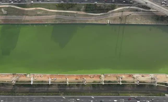 The Pinheiros River is green in Sao Paulo, Brazil, Tuesday, Sept. 10, 2024. The state's environmental authority attributes the river's new green hue to an algae bloom, the result of a severe drought that has significantly lowered water levels. (AP Photo/Andre Penner)