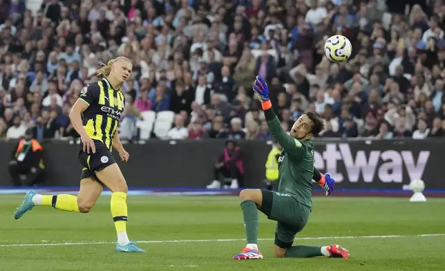 Manchester City's Erling Haaland, left, scores his side's third goal during the English Premier League soccer match between West Ham United and Manchester City at the London Stadium in London, England, Saturday, Aug. 31, 2024. (AP Photo/Frank Augstein)