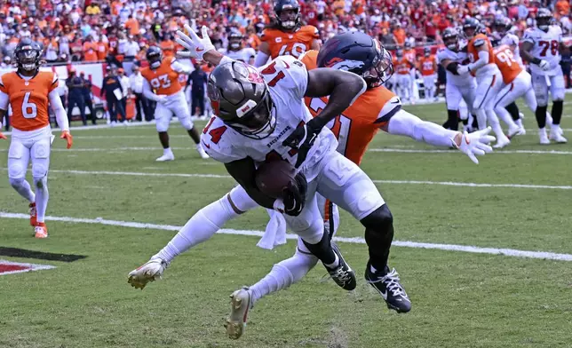 Tampa Bay Buccaneers wide receiver Chris Godwin makes a reception in front of Denver Broncos cornerback Riley Moss for a touchdown during the first half of an NFL football game, in Tampa, Fla. on Sunday, Sept. 22, 2024. (AP Photo/Jason Behnken)