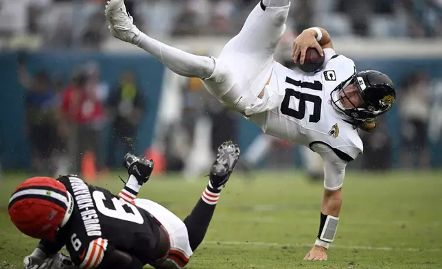 Jacksonville Jaguars quarterback Trevor Lawrence (16) leaps over Cleveland Browns linebacker Jeremiah Owusu-Koramoah (6) on a run during the second half of an NFL football game Sunday, Sept. 15, 2024, in Jacksonville, Fla. (AP Photo/Phelan M. Ebenhack)