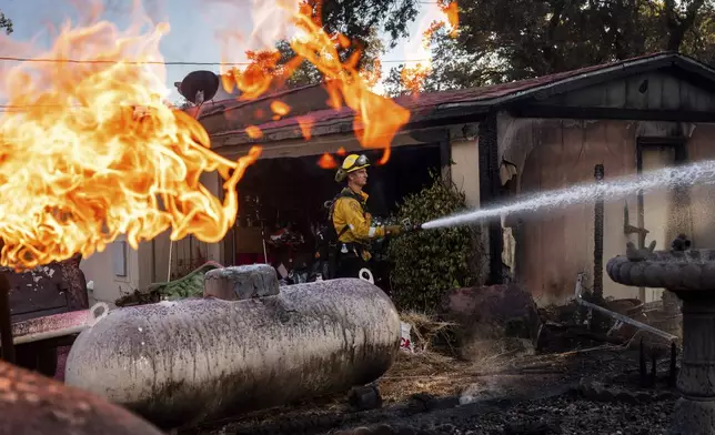 Firefighter Nolan Graham sprays water around a scorched garage as the Boyles fire burns in Clearlake, Calif., on Sunday, Sept. 8, 2024. (AP Photo/Noah Berger)