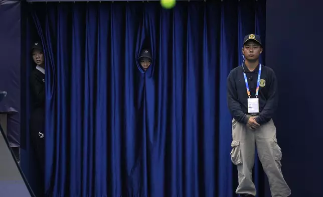 Workers peep through curtains to watch a match between France's Gael Monfils and Russia's Daniil Medvedev during the China Open tennis tournament held at the National Tennis Center in Beijing, Friday, Sept. 27, 2024. (AP Photo/Ng Han Guan)