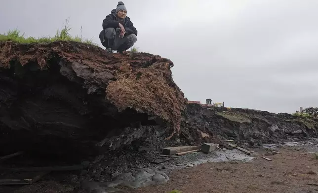 Charles Alexie stands along the coastal erosion that has eaten away at the riverbanks on Friday, Aug. 16, 2024, in Newtok, Alaska. (AP Photo/Rick Bowmer)