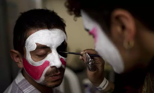 Participants paint each other's faces in preparation for a homemade gravity-powered vehicles race in Bogota, Colombia, Sunday, Sept. 29, 2024. (AP Photo/Ivan Valencia)