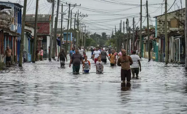 Residents wade through a street flooded in the passing of Hurricane Helene, in Batabano, Mayabeque province, Cuba, Thursday, Sept. 26, 2024. (AP Photo/Ramon Espinosa)