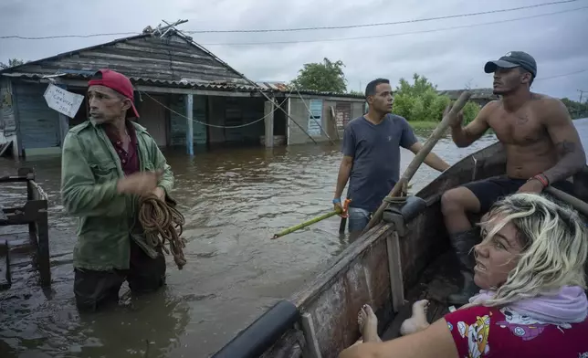 Neighbors chat on a flooded street after the passage of Hurricane Helene in Guanimar, Artemisa province, Cuba, Wednesday, Sept. 25, 2024. (AP Photo/Ramon Espinosa)