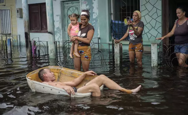 A man floats in a container on a street flooded by the passing of Hurricane Helene, in Batabano, Mayabeque province, Cuba, Thursday, Sept. 26, 2024. (AP Photo/Ramon Espinosa)