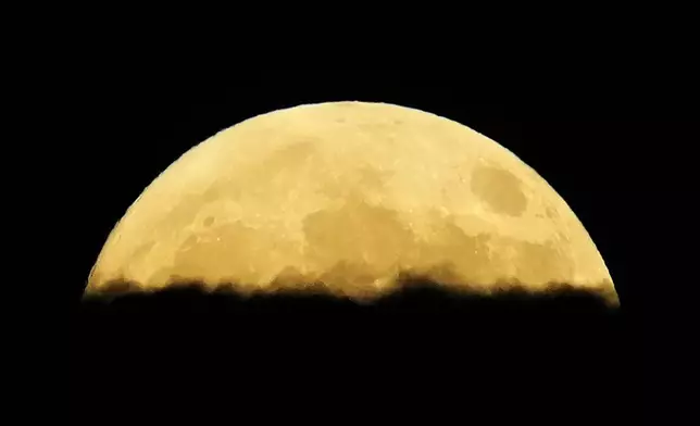 A supermoon rises behind clouds over Larnaca international airport in the eastern Mediterranean island of Cyprus, on Tuesday, Sept. 17, 2024. (AP Photo/Petros Karadjias)