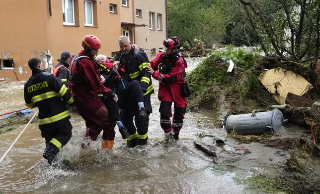 A resident is evacuated from her flooded house in Jesenik, Czech Republic, Sunday, Sept. 15, 2024. (AP Photo/Petr David Josek)