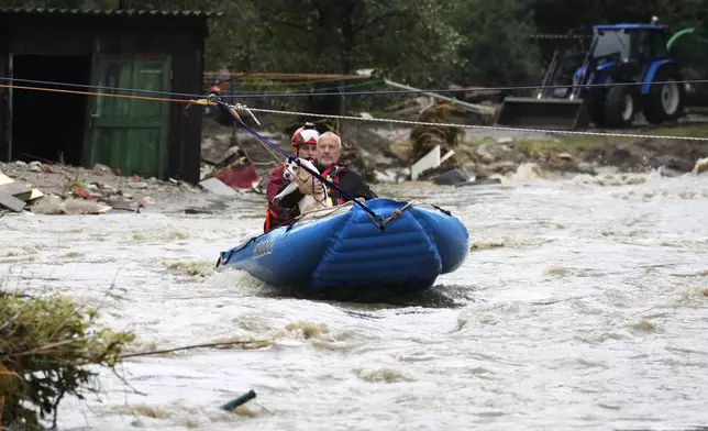 A resident with his dog is taken by a rubber boat from his flooded house in Jesenik, Czech Republic, Sunday, Sept. 15, 2024. (AP Photo/Petr David Josek)