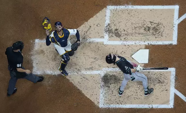 Arizona Diamondbacks' Corbin Carroll, right, and Milwaukee Brewers' Eric Haase, middle, look up at a foul ball during the second inning of a baseball game, Saturday, Sept. 21, 2024, in Milwaukee. (AP Photo/Aaron Gash)