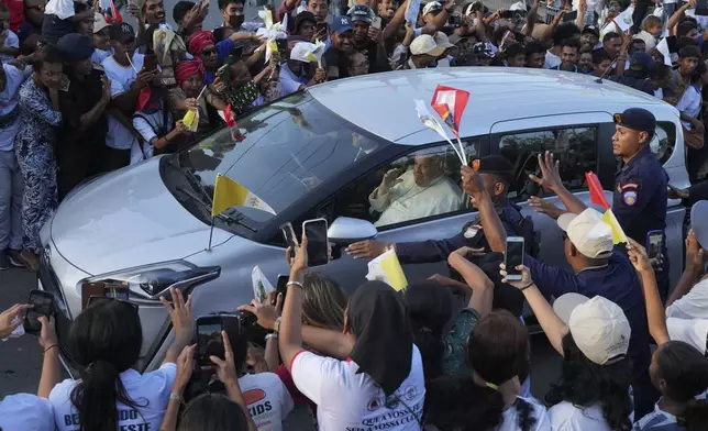 People greet Pope Francis as he travels in a car on way to the Presidential Palace in Dili, East Timor, Monday, Sept. 9, 2024. (AP Photo/Firdia Lisnawati)