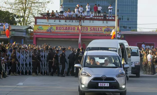 Pope Francis waves from his car as he arrives at the Presidential Palace for a welcome ceremony with President José Manuel Ramos-Horta in Dili, East Timor, Monday, Sept. 9, 2024. Pope Francis arrived in East Timor on Monday to encourage its recovery from a bloody and traumatic past and celebrate its development after two decades of independence from Indonesian rule. (AP Photo/Gregorio Borgia)