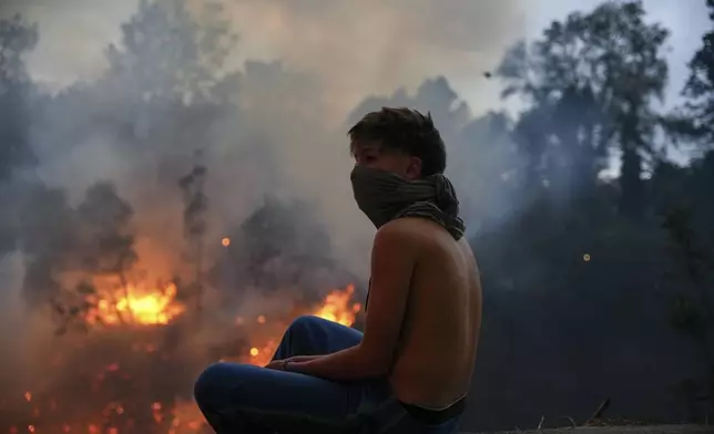 A resident watches fires burning in a forested area in the Guapulo neighborhood of Quito, Ecuador, Tuesday, Sept. 24, 2024. (AP Photo/Carlos Noriega)