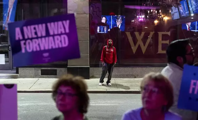 A pedestrian stops to watch a television across the street at Alley Cat showing the presidential debate between Republican presidential nominee former President Donald Trump and Democratic presidential nominee Vice President Kamala Harris, Tuesday, Sept. 10, 2024, in Providence, R.I. (AP Photo/David Goldman)