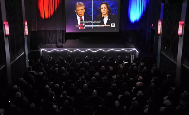 People watch the presidential debate between Republican presidential nominee former President Donald Trump and Democratic presidential nominee Vice President Kamala Harris at the Aztec theater Tuesday, Sept. 10, 2024, in Shawnee, Kan. (AP Photo/Charlie Riedel)