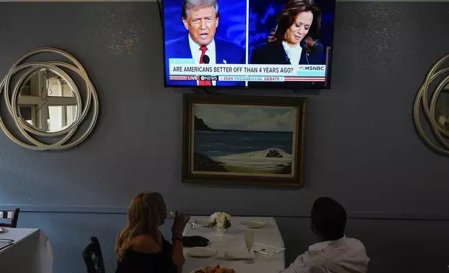 People watch the presidential debate between Republican presidential nominee former President Donald Trump and Democratic presidential nominee Vice President Kamala Harris, Tuesday, Sept. 10, 2024, in Oakland, Calif. (AP Photo/Godofredo A. Vásquez)