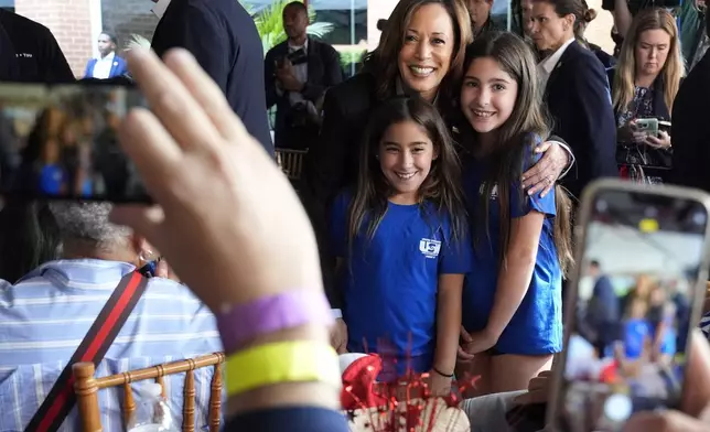 Democratic presidential nominee Vice President Kamala Harris poses for a photo with daughters of a union member as she campaigns with President Joe Biden at the IBEW Local Union #5 union hall in Pittsburgh, on Labor Day, Monday, Sept. 2, 2024. (AP Photo/Jacquelyn Martin)