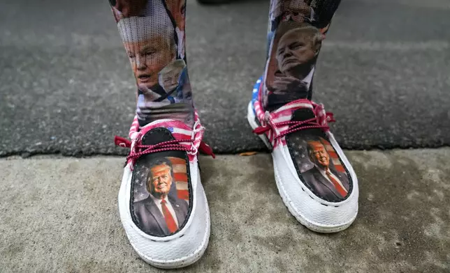 Republican presidential nominee former President Donald Trump is seen on the shoes of Nikki Nass of West Bend, Wis., as she waits in line for his arrival at a town hall, Thursday, Aug. 29, 2024, in La Crosse, Wis. (AP Photo/Charlie Neibergall)