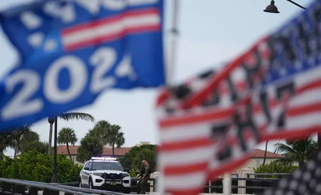 Police patrol on a bridge beside the Mar-a-Lago estate of Republican presidential nominee and former President Donald Trump, as a supporter flies flags to express support for Trump one day after an apparent assassination attempt, in Palm Beach, Fla., Monday, Sept. 16, 2024. (AP Photo/Rebecca Blackwell)