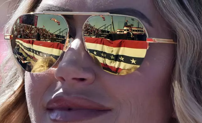 Republican presidential nominee former President Donald Trump is reflected in the sunglasses of Lara Trump at a campaign rally at Wilmington International Airport, Saturday, Sept. 21, 2024, in Wilmington, N.C. (AP Photo/Alex Brandon)