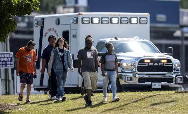 Students and parents walk off campus at Apalachee High School, Wednesday, Sept. 4, 2024, in Winder, Ga. A shooting at the Georgia high school Wednesday caused an unknown number of injuries and a suspect was arrested in a chaotic scene. (AP Photo/Mike Stewart)