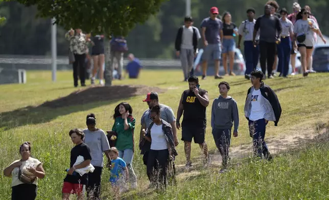 Students and parents walk off campus at Apalachee High School, Wednesday, Sept. 4, 2024, in Winder, Ga. (AP Photo/Mike Stewart)