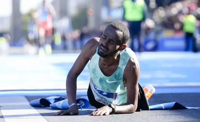 Milkesa Mengesha from Ethiopia lays on the ground and reacts after he crosses the finish line to win the men's division of the Berlin Marathon in Berlin, Germany, Sunday, Sept. 29, 2024. (AP Photo/Ebrahim Noroozi)