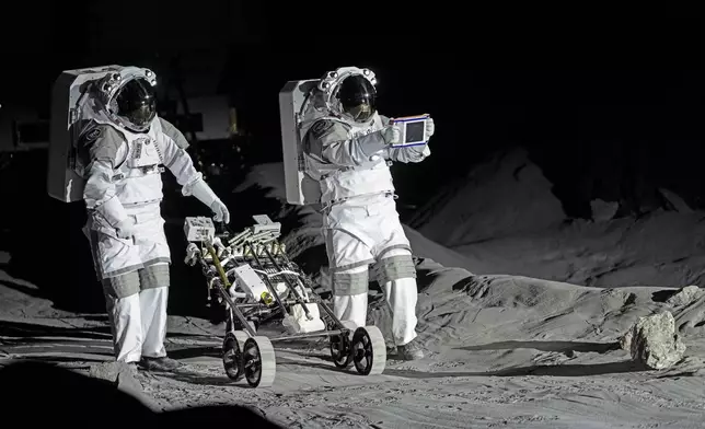 Astronauts Thomas Pesquet of France and Matthias Maurer of Germany demonstrate their training in lunar surface simulating conditions for future moon missions, like the Artemis lunar exploration program led by NASA, at the opening of the new LUNA facility at the European Astronaut Center in Cologne, Germany, Wednesday, Sept. 25, 2024. (AP Photo/Martin Meissner)