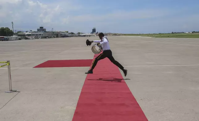 A member of the Police Music Band jumps over the welcome mat before the arrival of Kenya's President William Ruto at the Toussaint Louverture International Airport in Port-au-Prince, Haiti, Saturday, Sept. 21, 2024. (AP Photo/Odelyn Joseph)