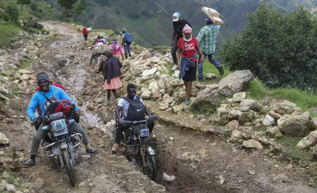 People traverse mountainous roads as they avoid gang violence in the Kenscoff neighborhood of Port-au-Prince, Haiti, Tuesday, Sept. 10, 2024. (AP Photo/Odelyn Joseph)