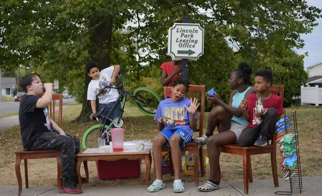 Neighborhood kids gather to sell Kool-Aid and chips, Tuesday, Sept. 17, 2024, in Springfield, Ohio. Some were kept home from school because of the bomb threats at their schools, and if that happens again, they plan to be at the corner with Kool-Aid and chips again tomorrow. (AP Photo/Carolyn Kaster)