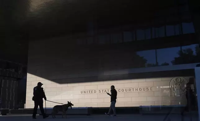 A police officer inspects the exterior of a federal courthouse with the aid of a canine at the start of Hunter Biden's trial on felony tax charges Thursday, Sept. 5, 2024, in Los Angeles. (AP Photo/Jae C. Hong)