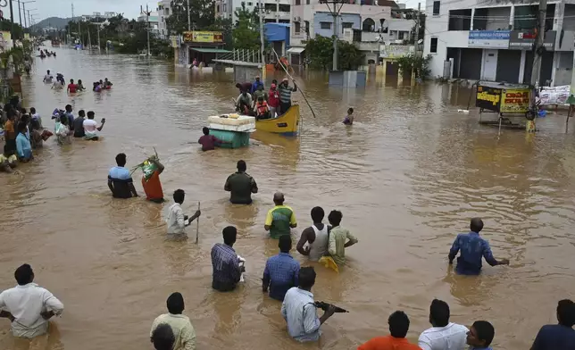 People wade through a flooded road after heavy rains in Vijayawada, India, Monday, Sept. 2, 2024. (AP Photo)