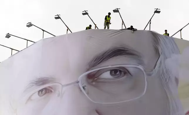 Workers install a huge portrait of slain Hezbollah leader Hassan Nasrallah on a building at Enqelab-e-Eslami (Islamic Revolution) Sq. in Tehran, Iran, Sunday, Sept. 29, 2024. (AP Photo/Vahid Salemi)