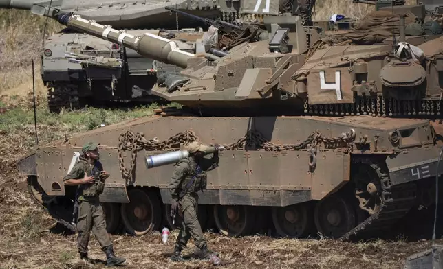 An Israeli soldier carries a shell next to a tank in northern Israel on Friday, Sept. 27, 2024. (AP Photo/Baz Ratner)