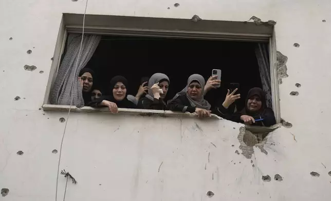 Mourners watch the funeral of Palestinian men who were killed during an Israeli military operation, from a building damaged with bullet holes, in Jenin, West Bank, Friday, Sept. 6, 2024. (AP Photo/Majdi Mohammed)