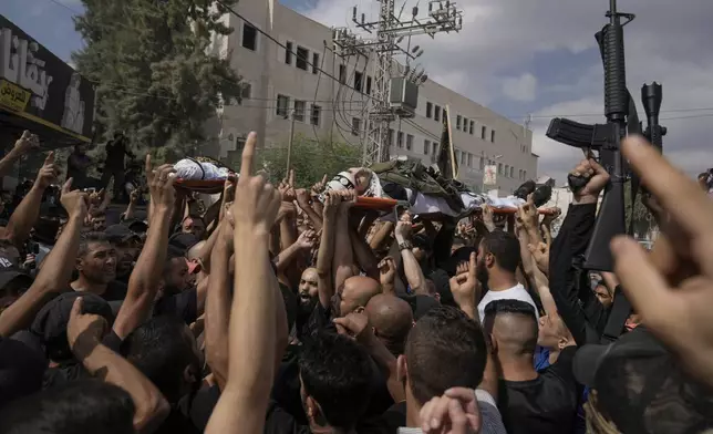 Mourners, some armed, carry the bodies of Palestinian men who were killed during an Israeli military operation, draped in the Islamic Jihad militant group flags, during their funeral in Jenin, West Bank, Friday, Sept. 6, 2024. (AP Photo/Majdi Mohammed)