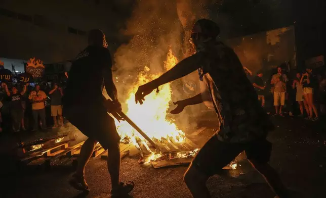 Demonstrators light a bonfire during a protest demanding a cease-fire deal and the immediate release of hostages held by Hamas in the Gaza Strip after the deaths of six hostages in the Palestinian territory, in Tel Aviv, Israel, on Monday, Sept. 2, 2024. (AP Photo/Ariel Schalit)